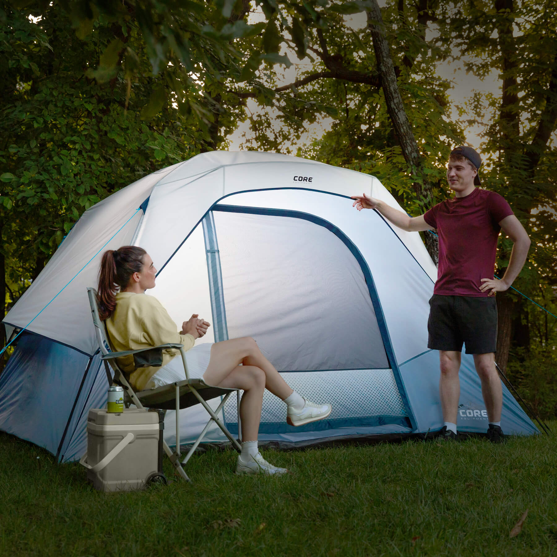 CORE 6 person lighted dome tent in gray win blue glowing at a campsite, showcasing built-in interior lighting and weather protection.