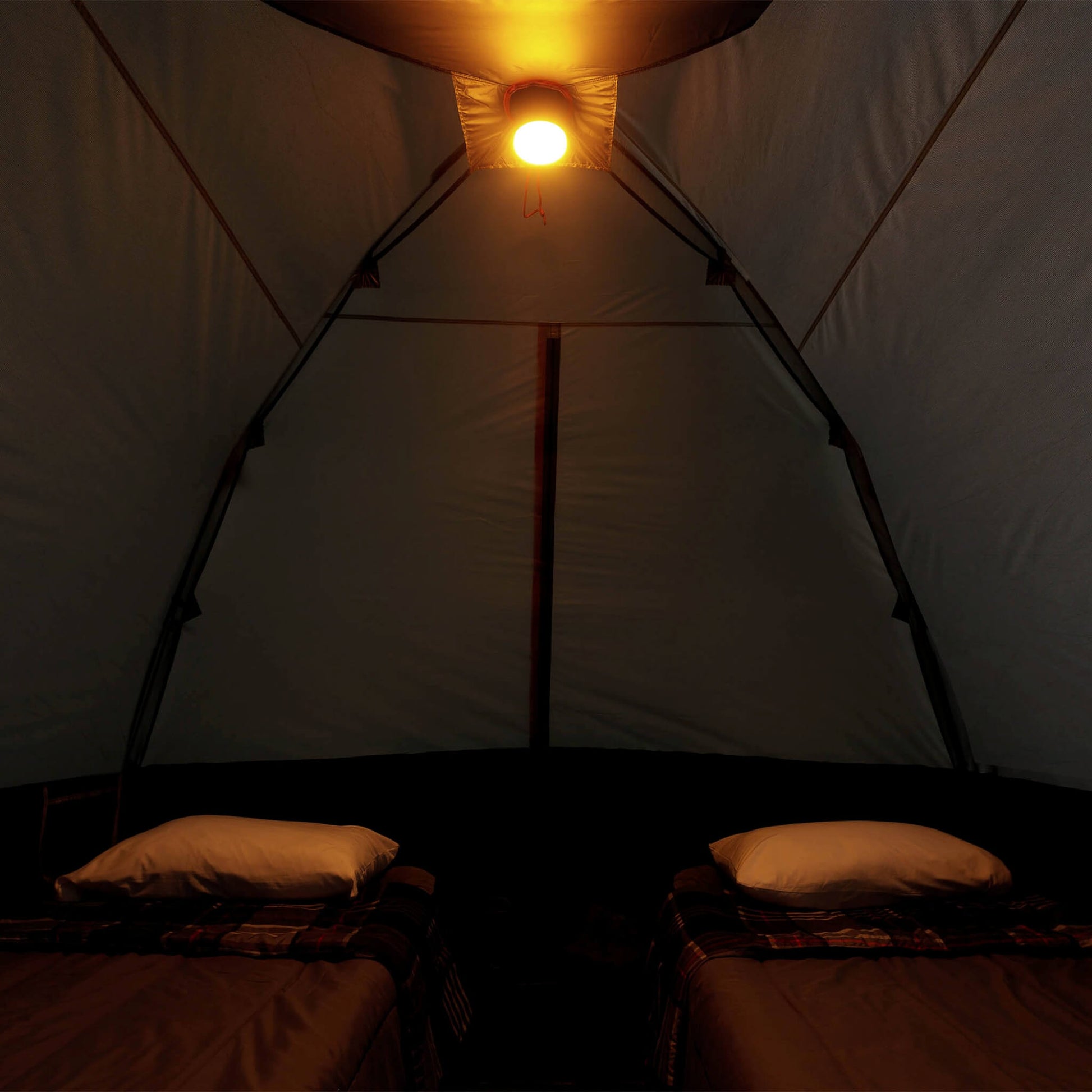 Inside view of CORE 6 person lighted dome tent with two cots, dark interior, and ceiling light on amber mode providing overhead illumination.