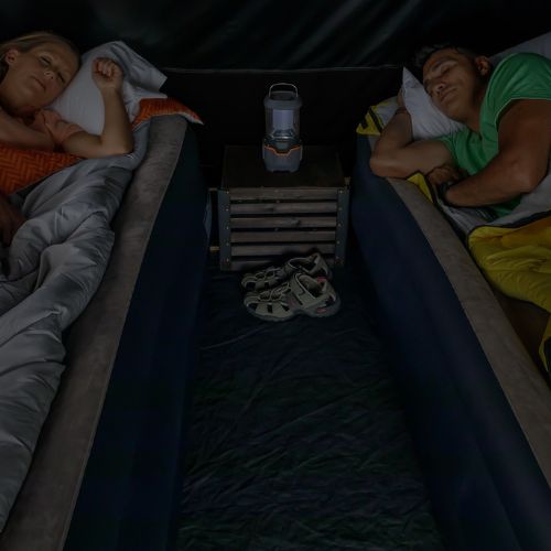 Two people are lying in a bed in a CORE Blockout tent.