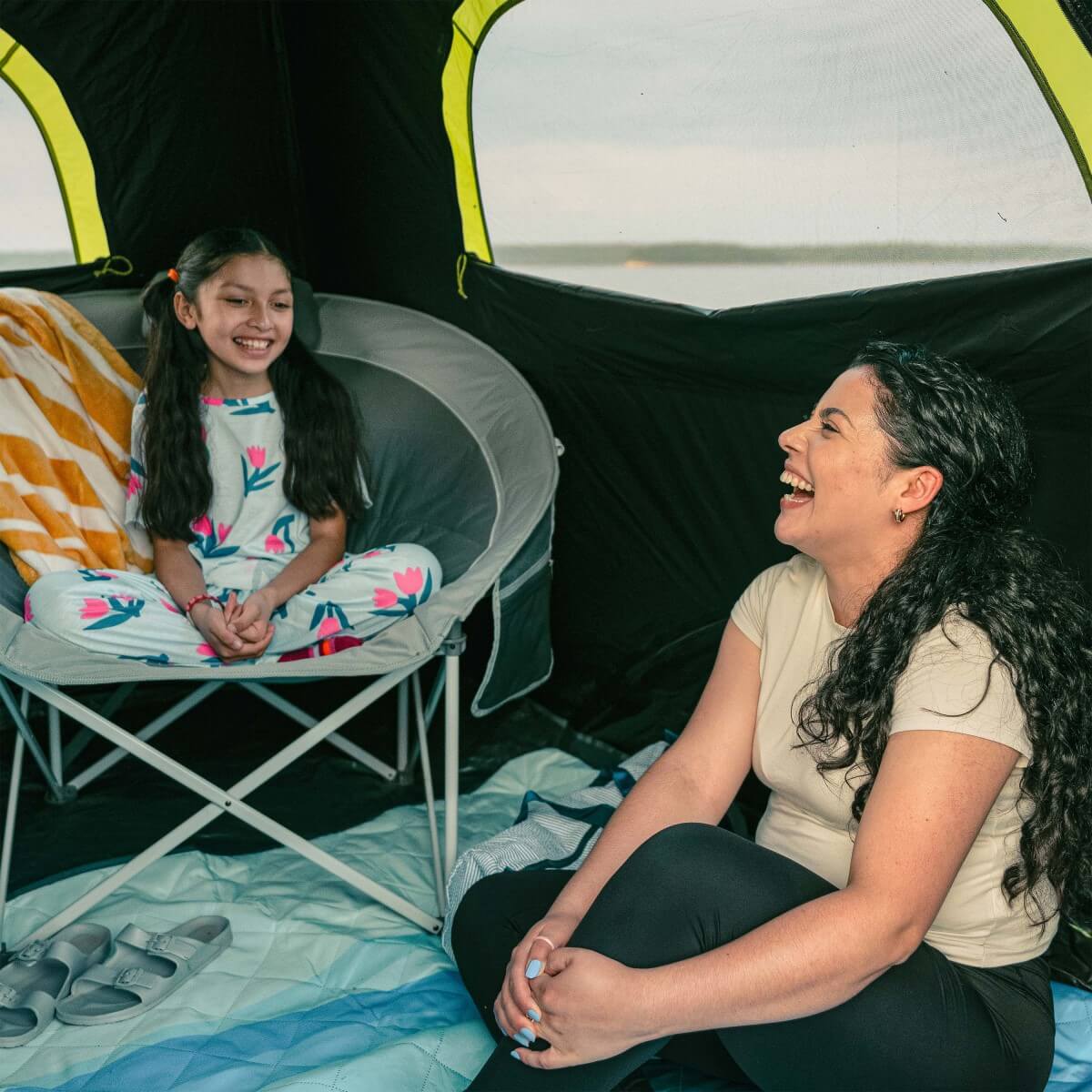 Two people sitting inside a CORE 6 person Blockout instant tent, one adult and one child, smiling and laughing.