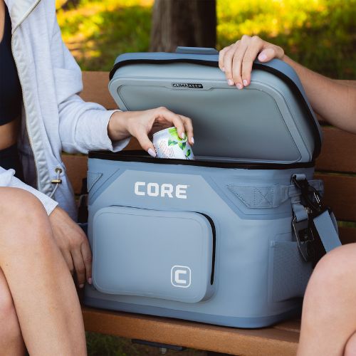 A person is opening a blue 18-can soft cooler on a park bench.