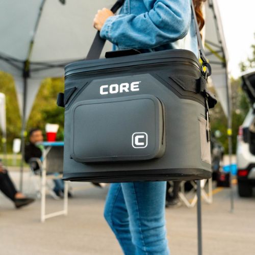 A person carrying a CORE 18 can cooler outdoors at a tailgate.