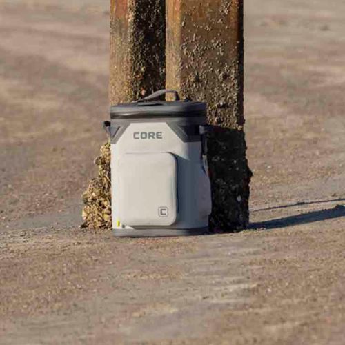 A gray CORE 24 can backpack cooler sitting next to a beach pier.