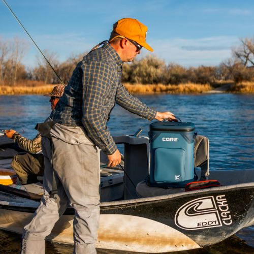 A man on a boat with a cooler labeled 'CORE' near a body of water.