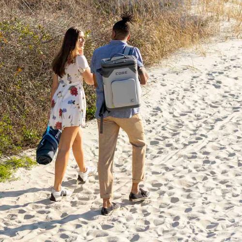 Two people walking on a sandy path with a CORE 24 can backpack cooler.