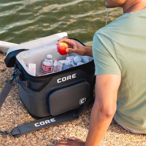 A person opening a CORE cooler by a body of water.