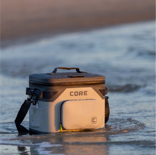 A CORE cooler is partially submerged in water near a beach.