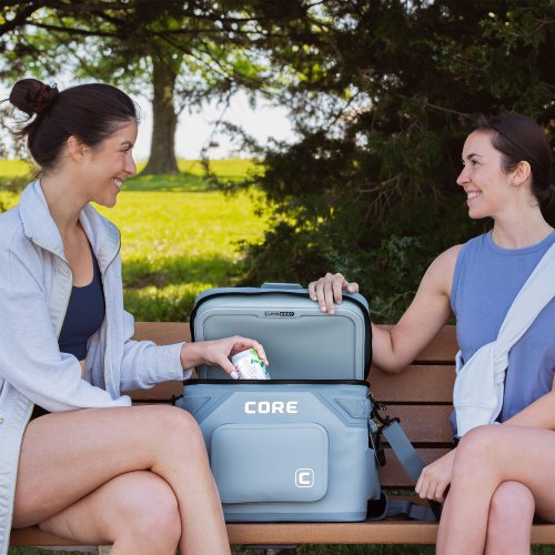 Two women sitting on a bench outdoors with a CORE Climkaeep cooler.