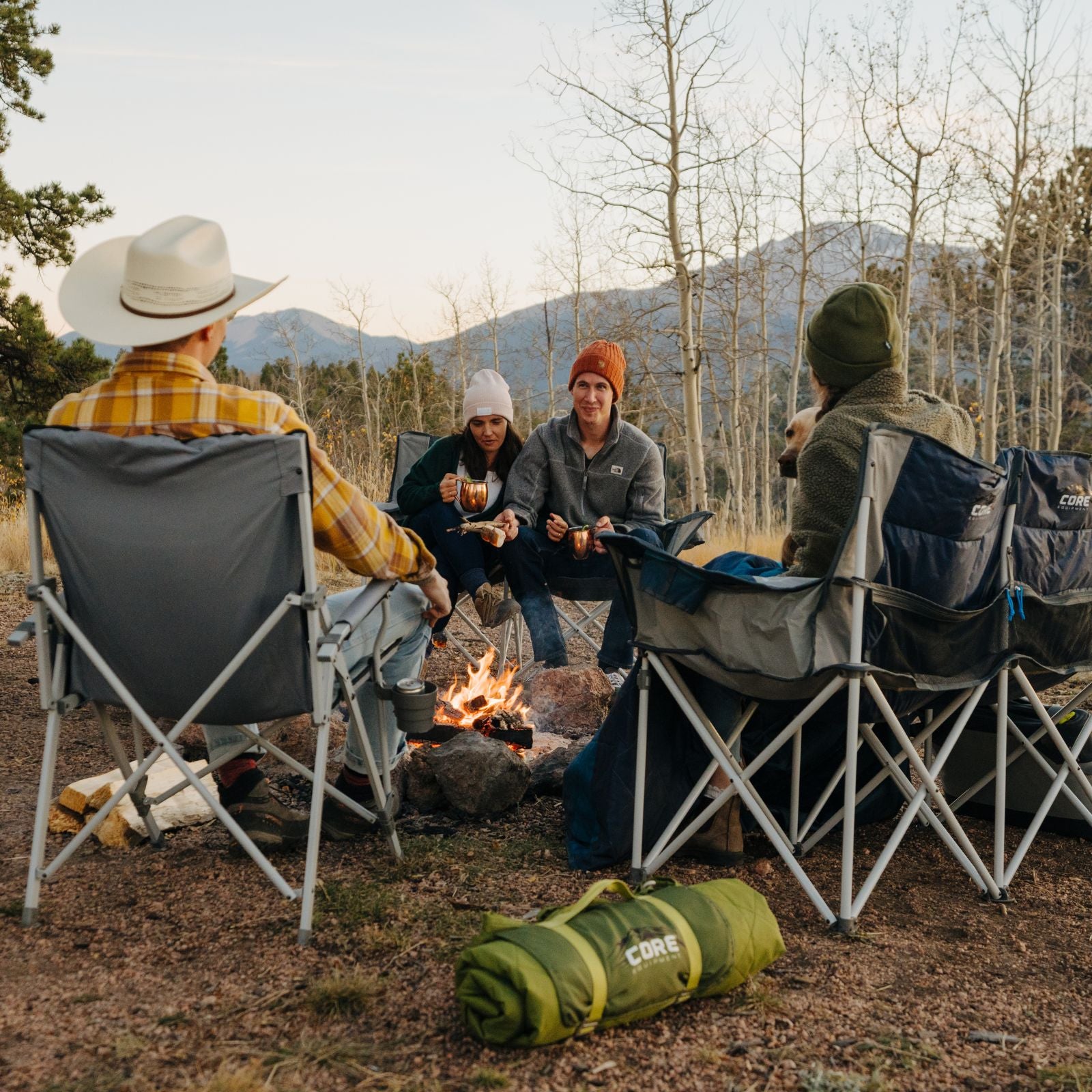 A group of friends relaxing around a fire sitting in CORE chairs. 