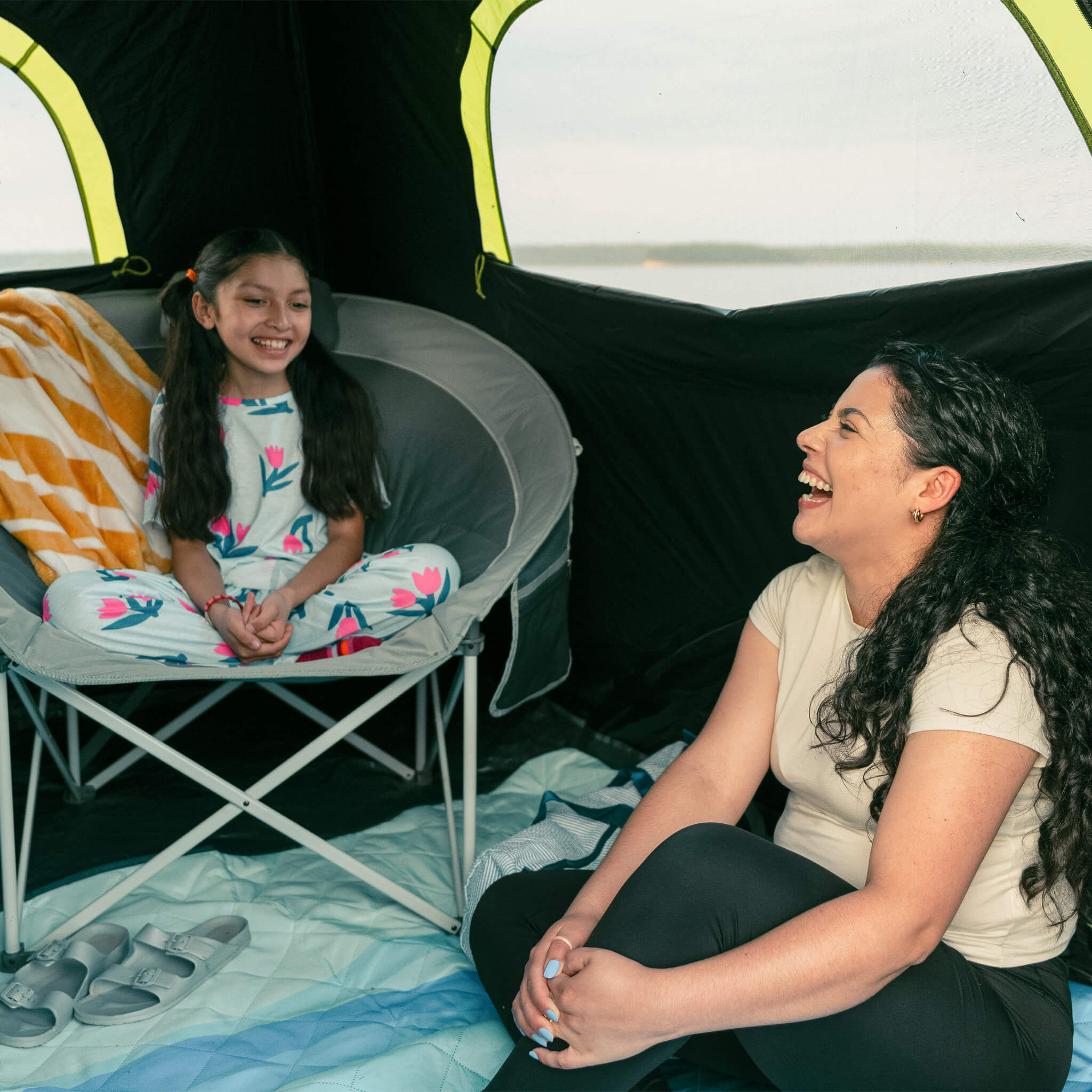 Mother and daughter relaxing inside a tent with a CORE gray moon chair.