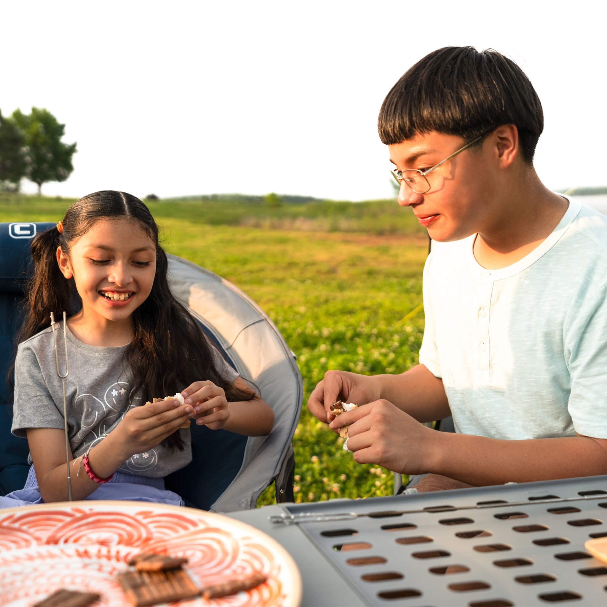Campers sitting outdoors near the CORE cook table with a CORE padded moon chair.