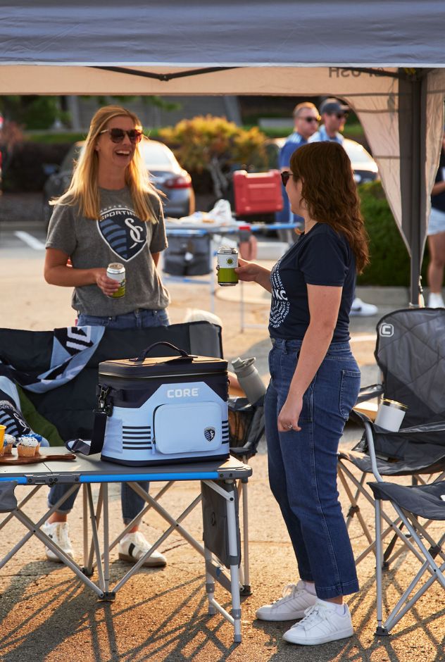Two women standing next to a Core cooler at an outdoor event.