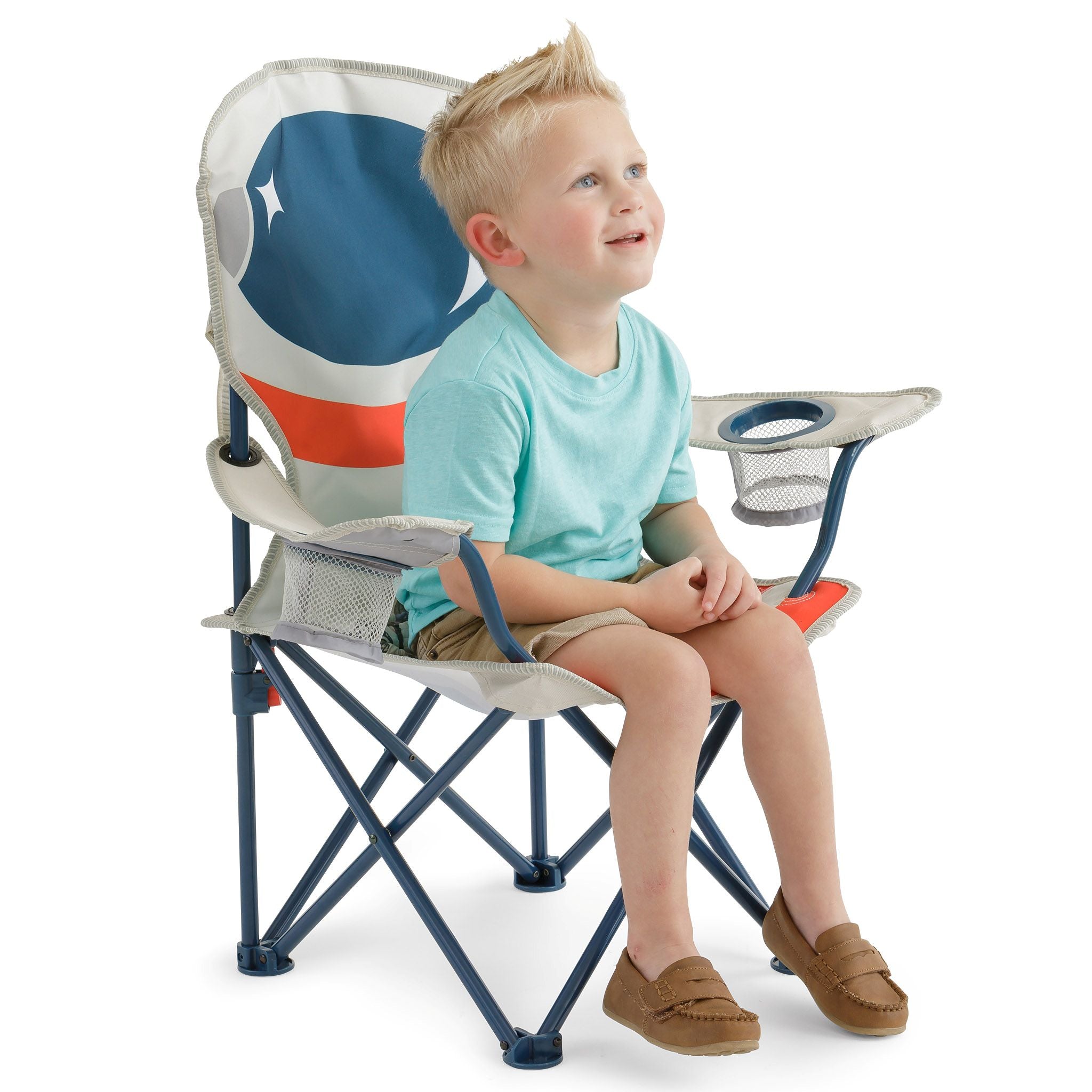 A young boy sitting on a folding camp chair with a space-themed backrest, featuring a blue, white, and orange design, set against a plain white background.