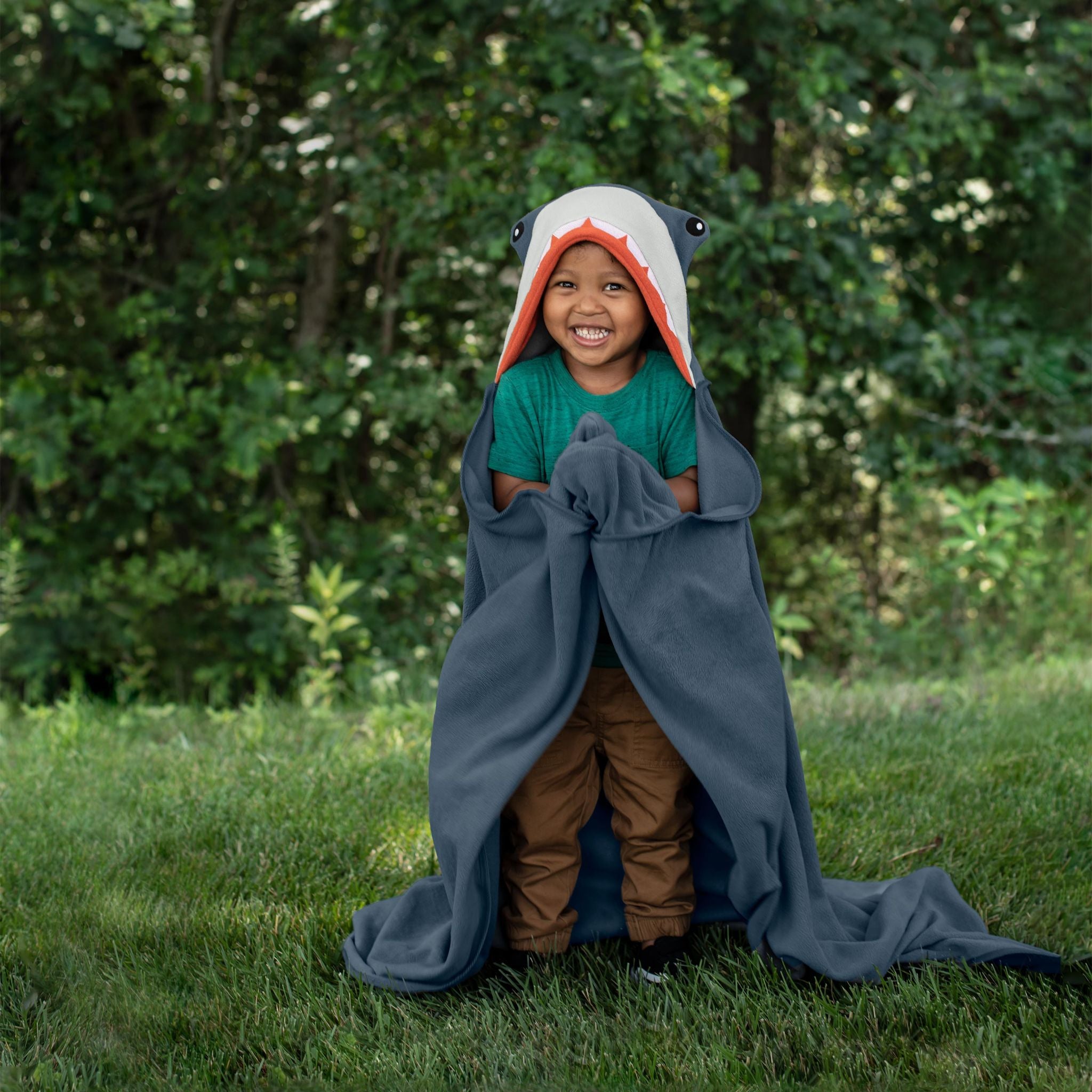 A child wearing a shark-themed hooded blanket outdoors.