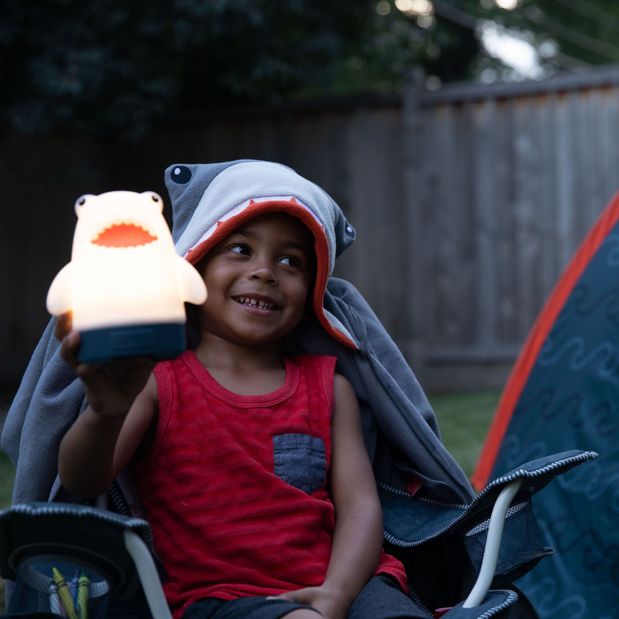 A child holding a shark lantern in a backyard setting.