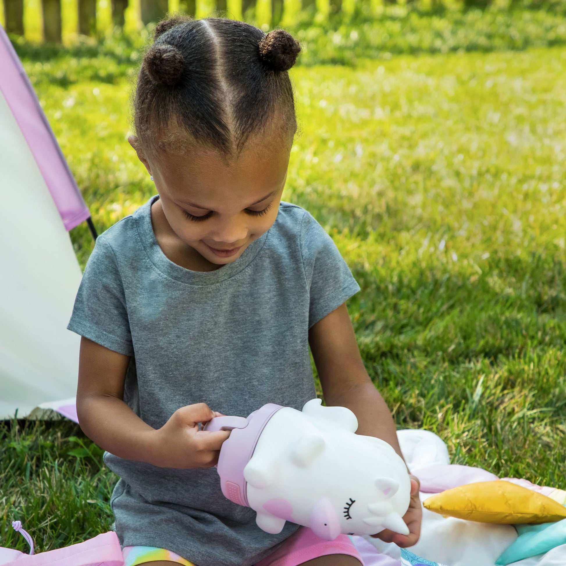 A child playing with a unicorn-shaped lantern in a grassy outdoor setting.
