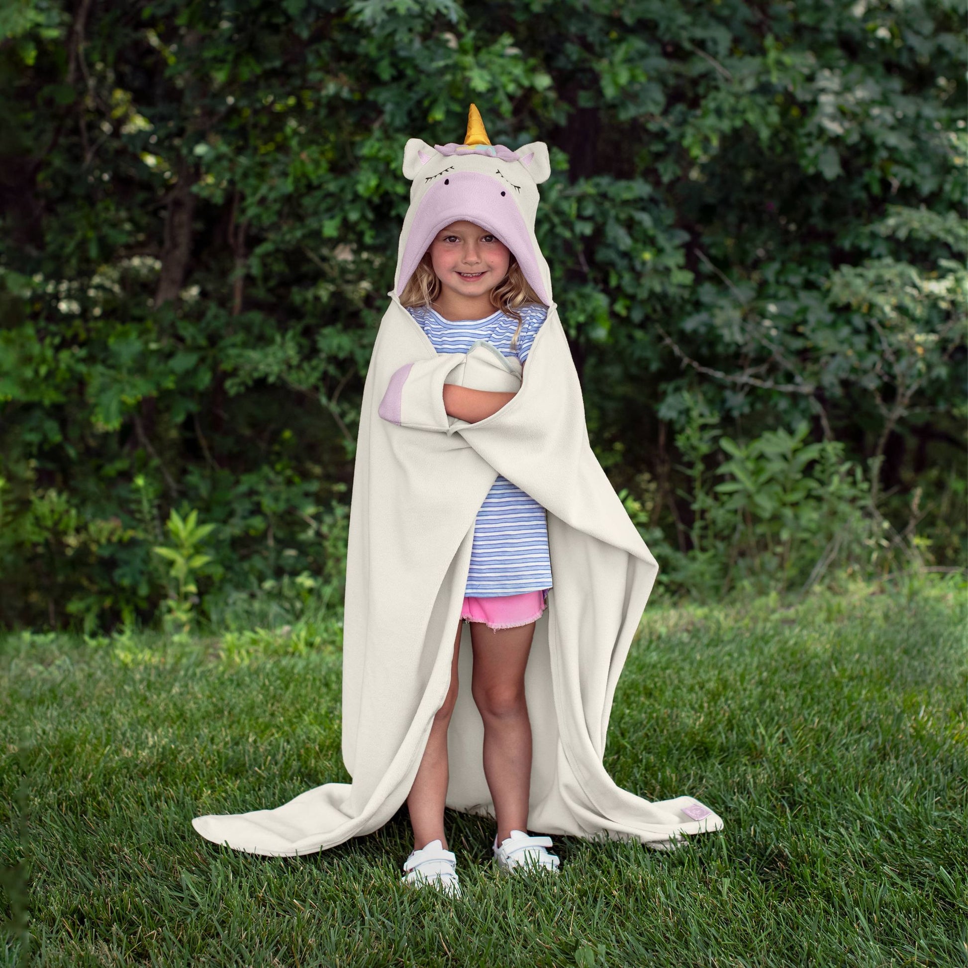 A child wearing a unicorn-themed hooded blanket outdoors.
