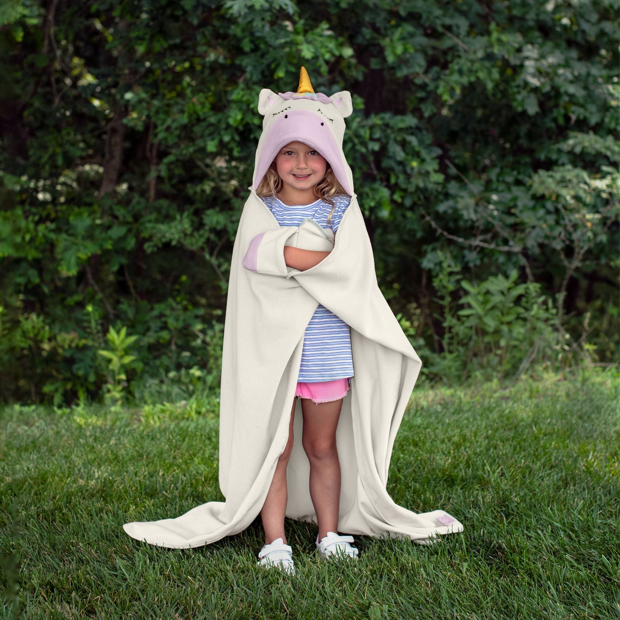 A child wearing a unicorn-themed hooded blanket outdoors.