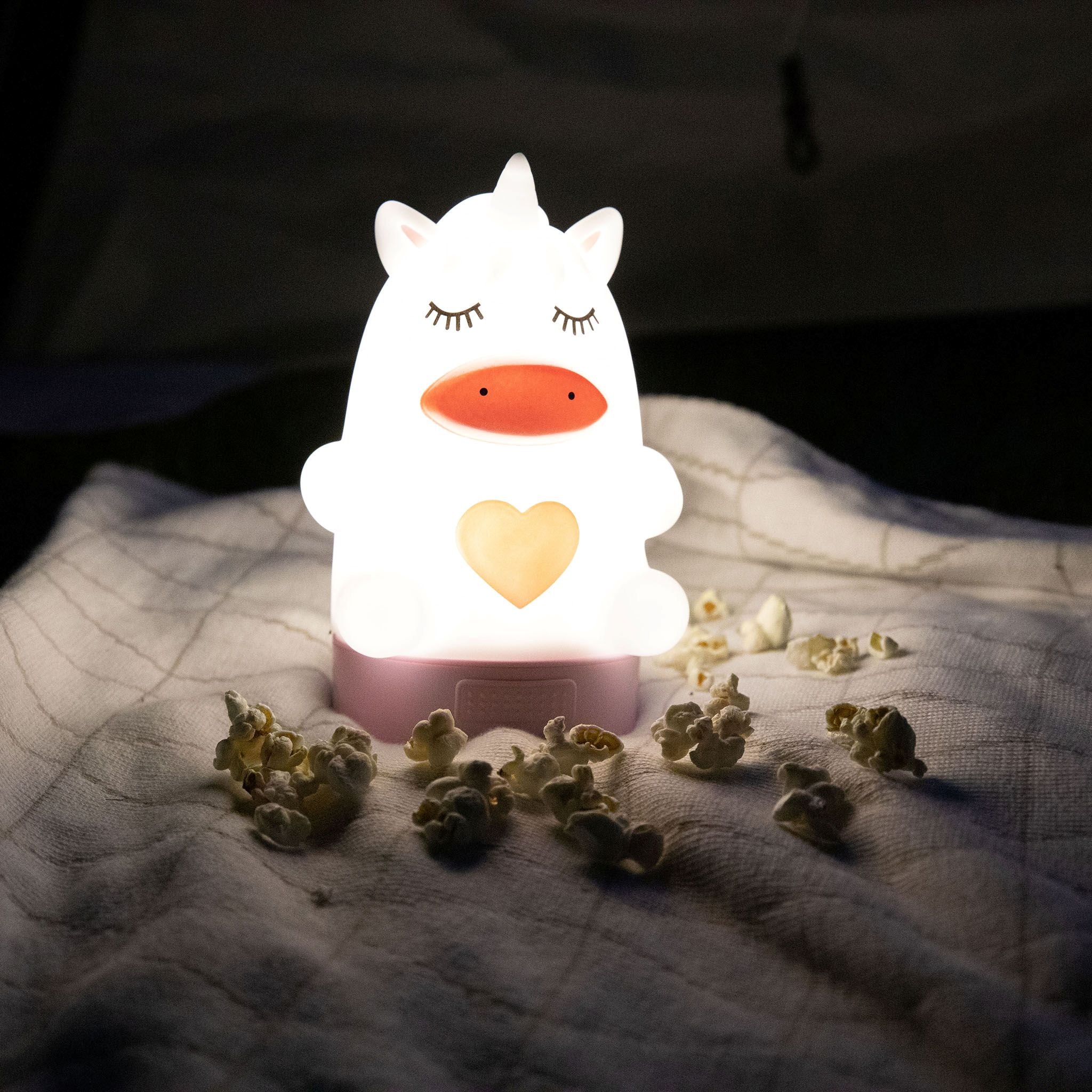 Unicorn-shaped night light sitting on a blanket.