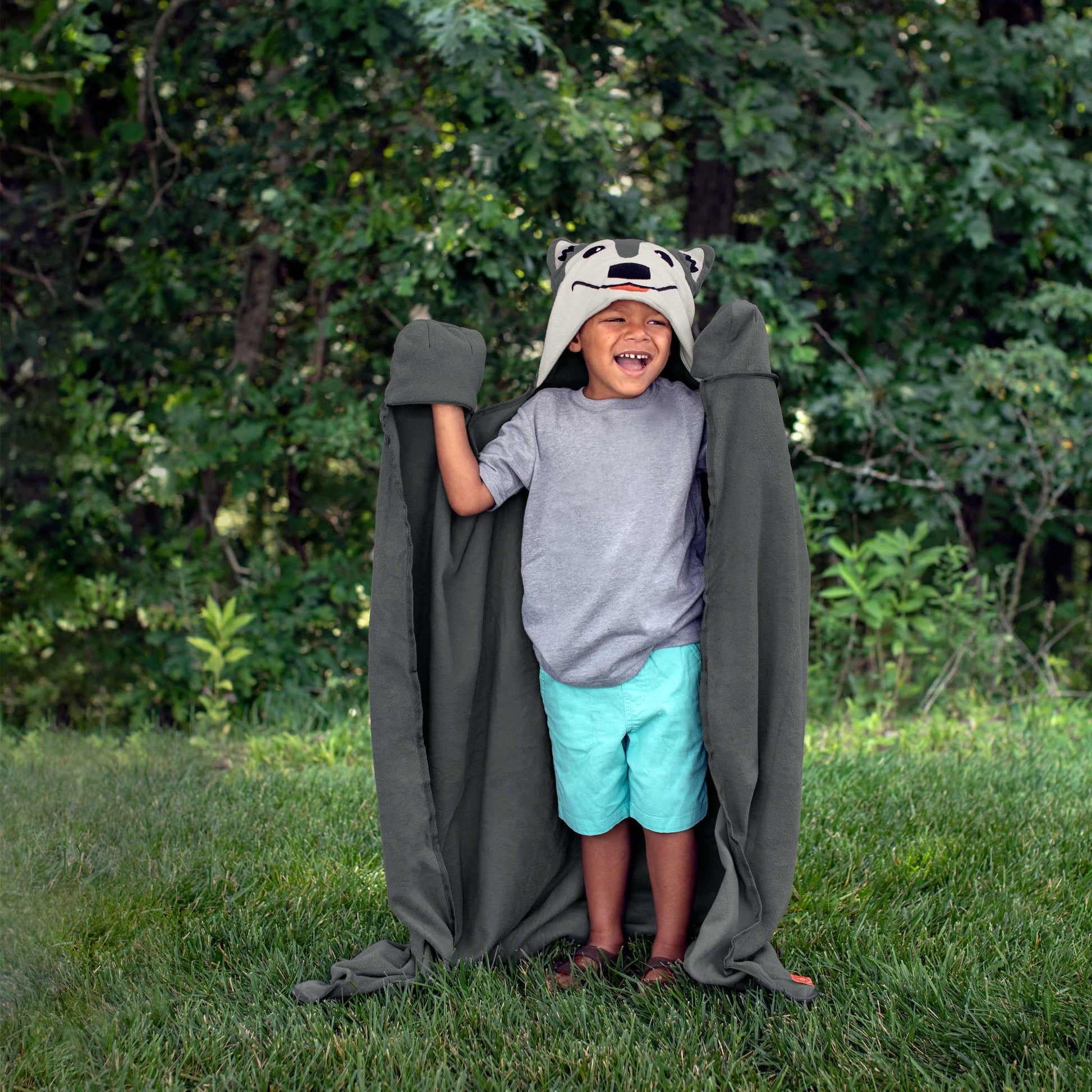A child wearing a wolf-themed hooded blanket outdoors.
