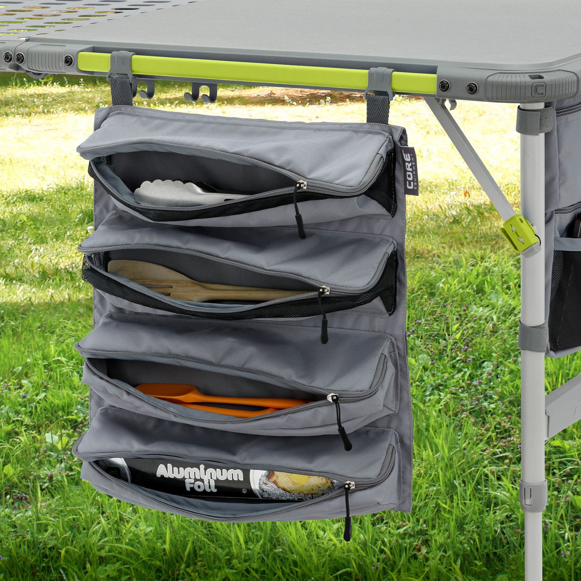 Gray camping organizer hanging from a tent pole with grass in the background
