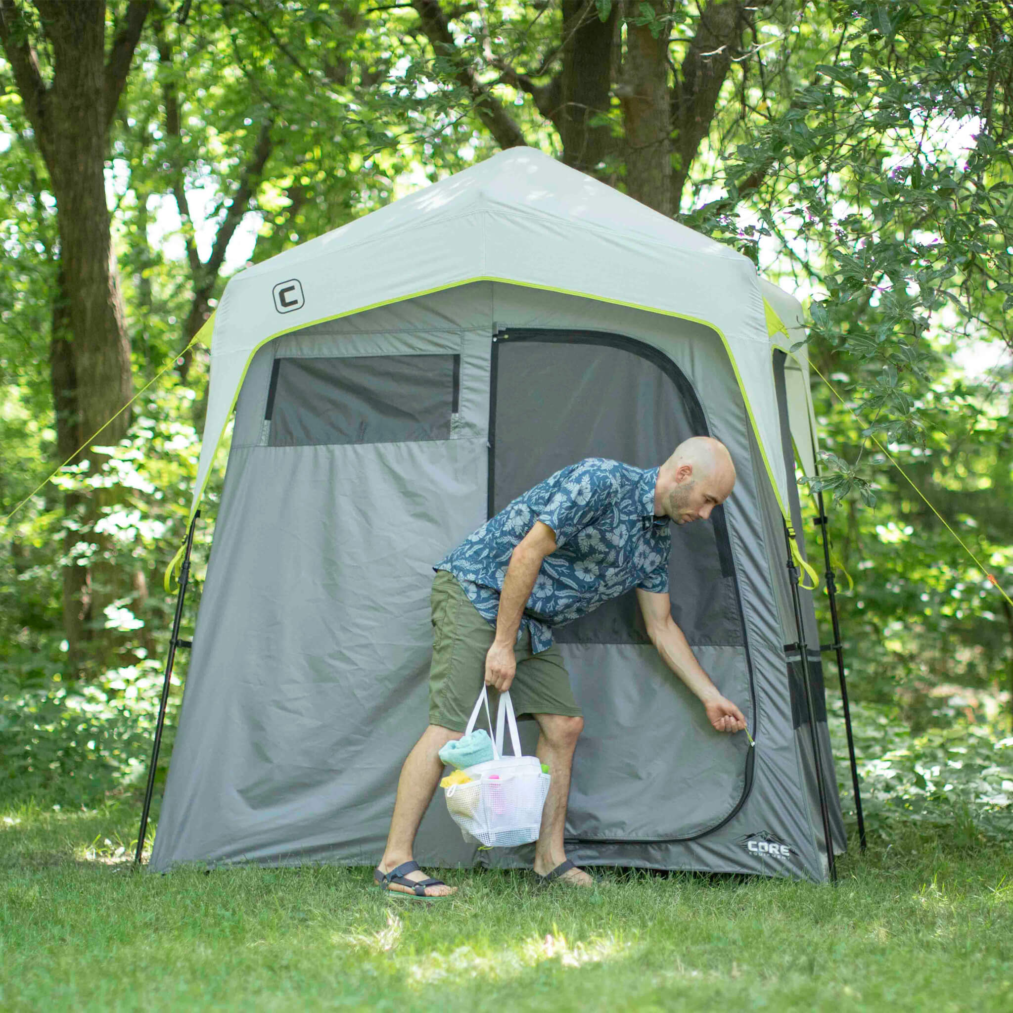 Camper using the CORE instant shower tent outdoors, highlighting easy access, durable design, and privacy for camping trips.