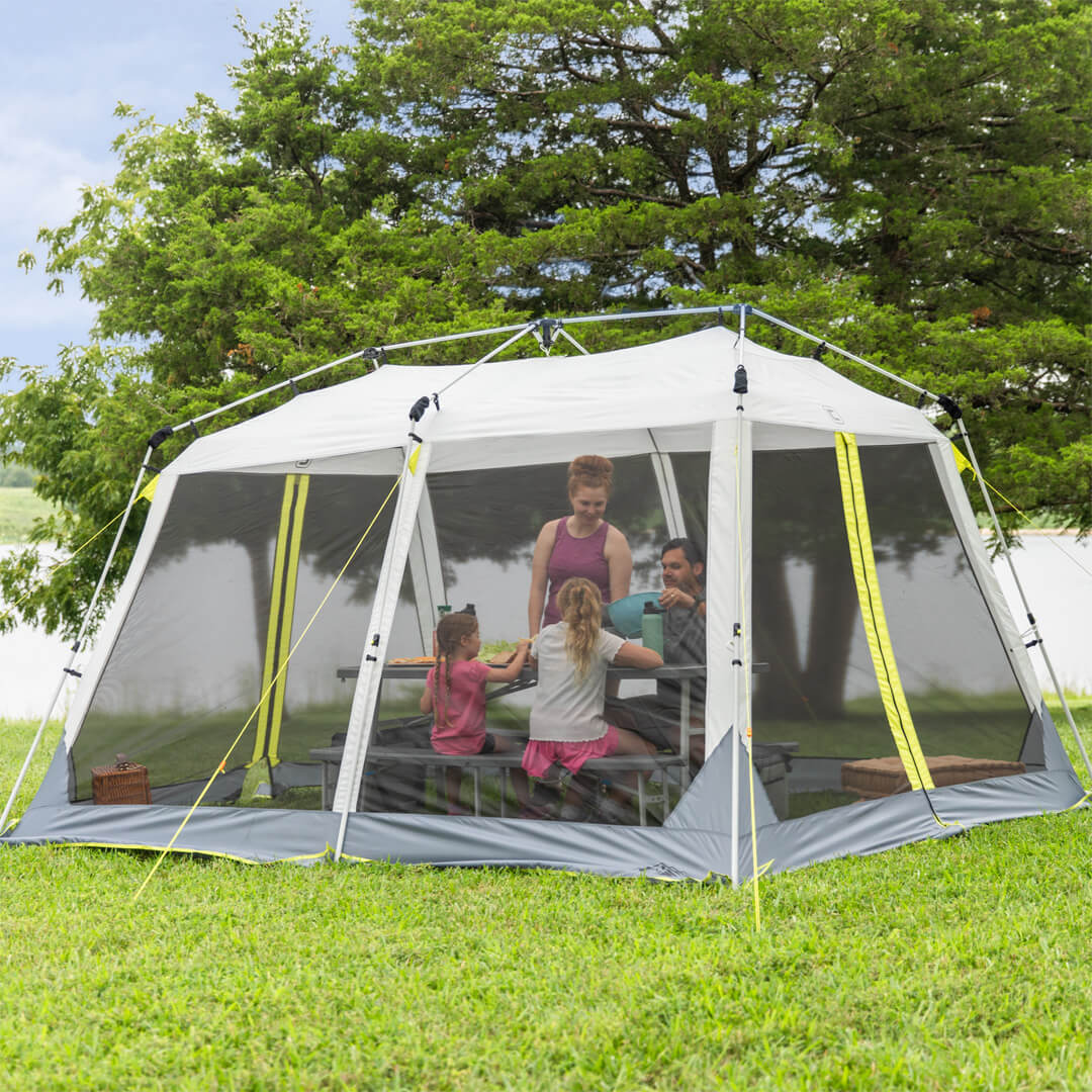 Family sitting inside a core 12x10 instant screen house surrounded by trees and grass.