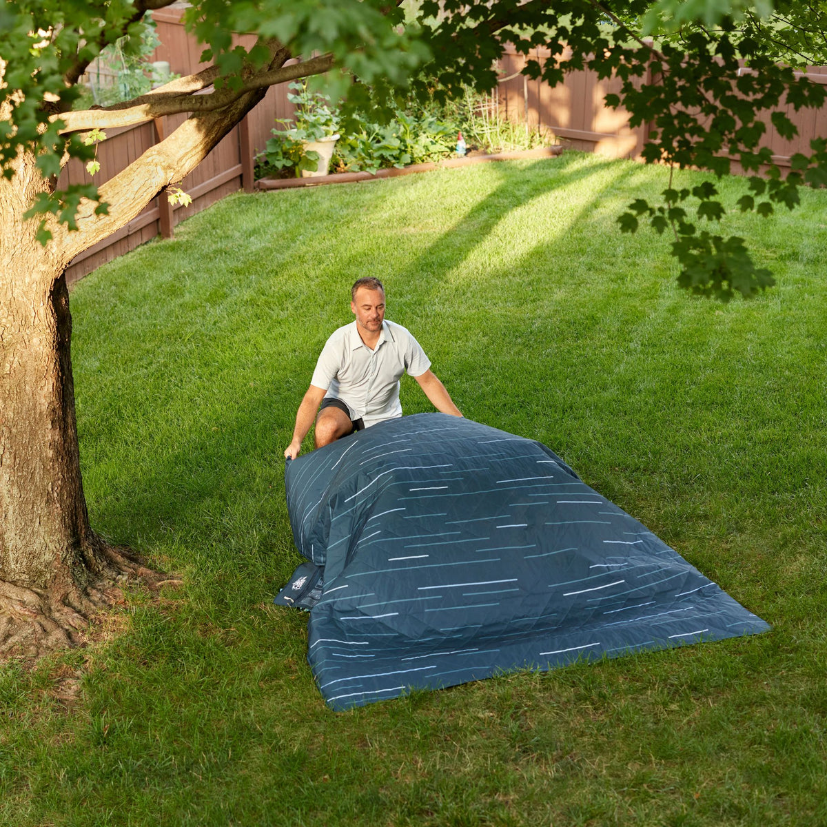 A person is laying out the blanket in the grass.