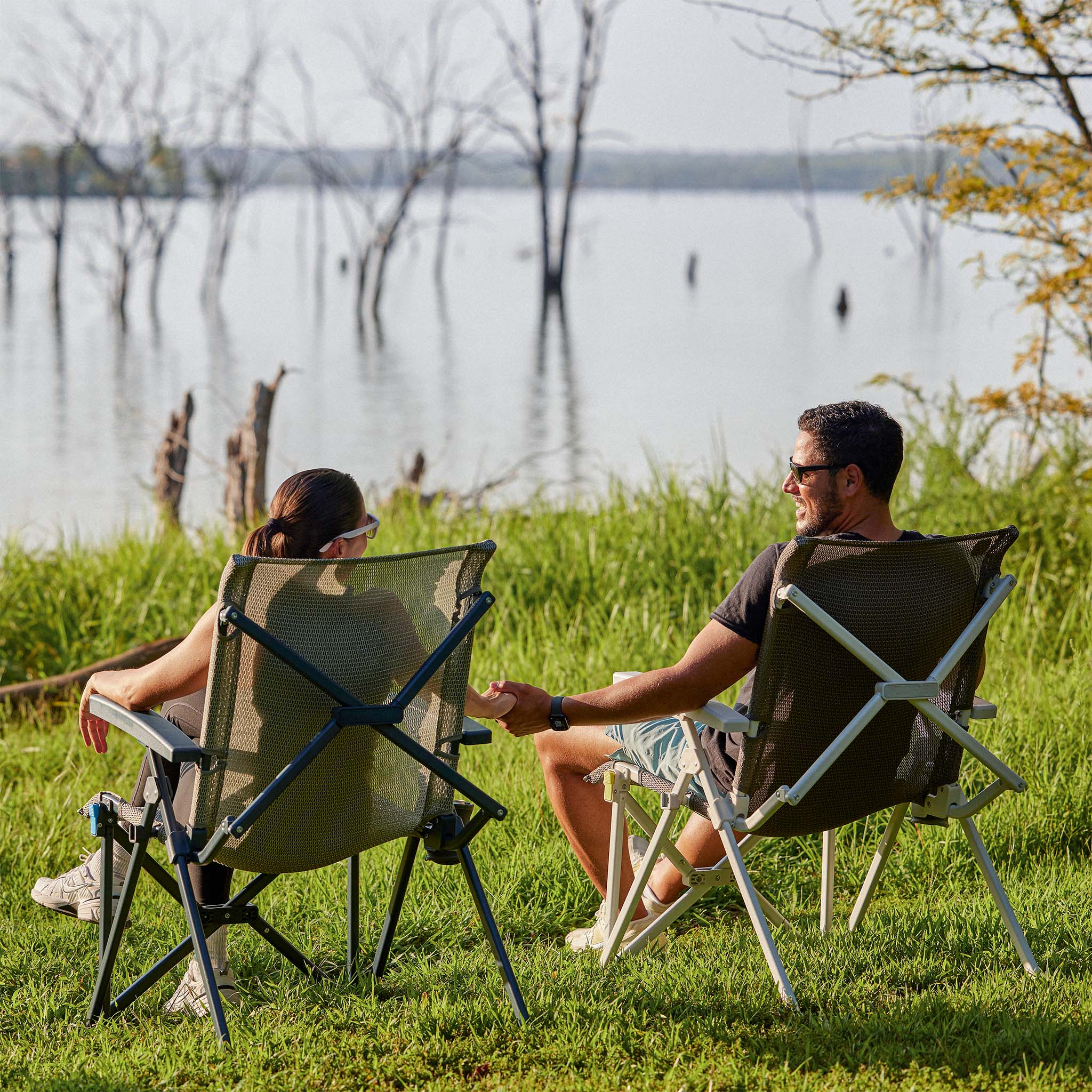 Two people relaxing outdoors in CORE performance hard arm chairs by the water.