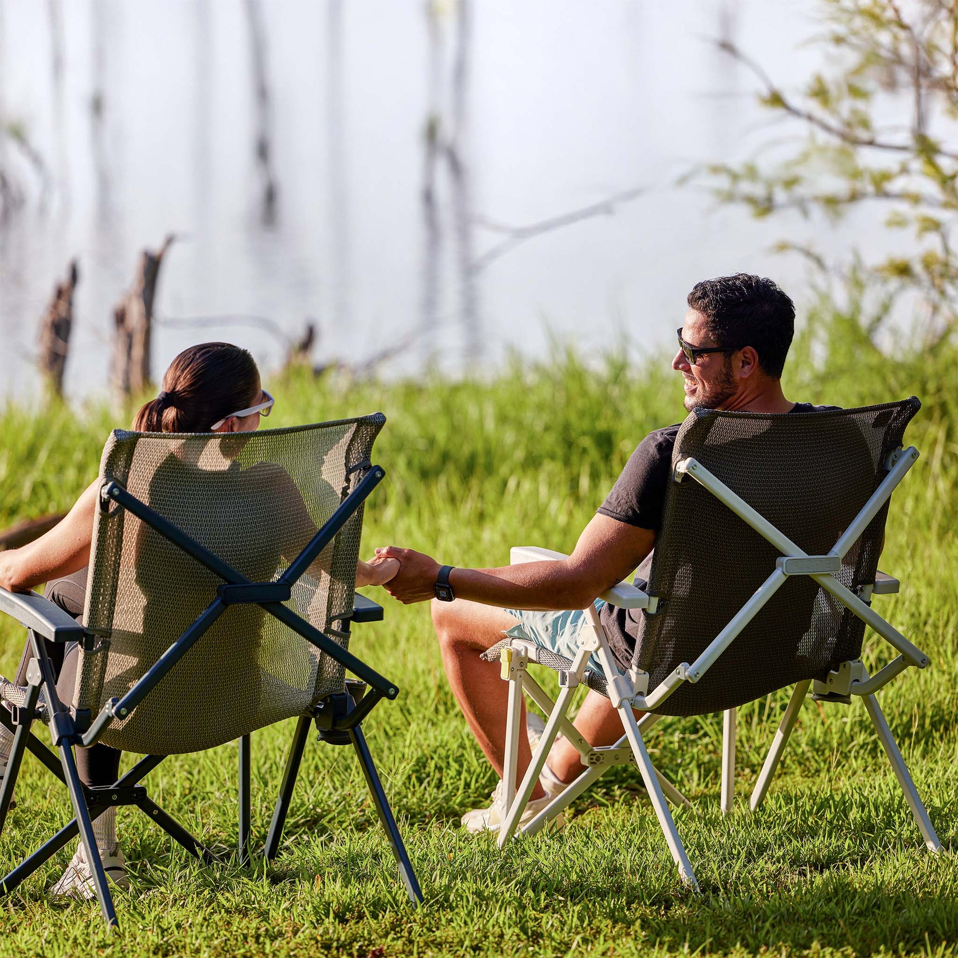 Two people relaxing outdoors in CORE performance hard arm chairs by the water.