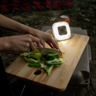 Lifestyle image of tent light propped up on cutting board illuminating person cutting peppers