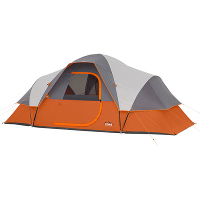 A large 9 Person Extended Dome Tent with an orange and grey color scheme. The tent has a zipper door in the middle, mesh windows, and several stakes and guy lines for securing it. The "CORE" logo is visible on the side of the tent.