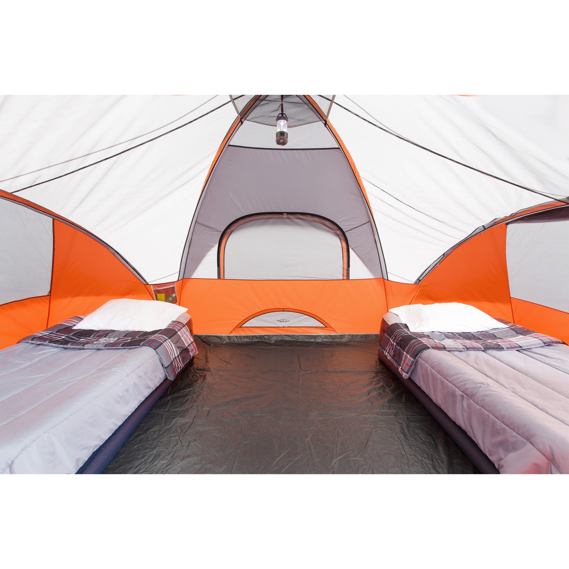 Inside view of an orange and gray CORE 9 Person Extended Dome Tent set up for camping with two sleeping bags on inflatable mattresses placed on either side. A lantern hangs from the ceiling. The sleeping bags, topped with plaid blankets, are cozy and inviting. At the back of the tent is a window with a mesh screen, perfect for enjoying the outdoor sights while keeping bugs out.