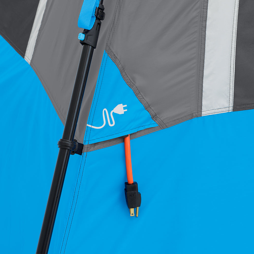 A close-up of the interior of a blue and gray 12 Person Lighted Instant Cabin Tent by CORE shows a red electrical cord extending through a designated port in the tent wall. The port is marked with a white outline of a plug, indicating where electrical cords can be passed through, making outdoor adventures more convenient.
