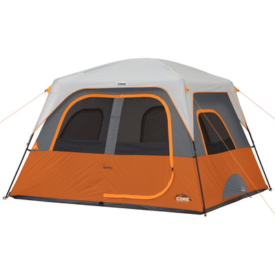 A large orange and gray 6 Person Straight Wall Cabin Tent with a domed gray roof and multiple windows with mesh screens. The tent features CORE branding and has several orange guy lines for support. The front door is zippered and features an additional fabric cover.