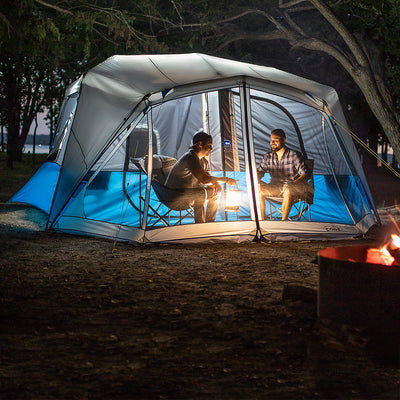 10 Person Lighted Instant Cabin Tent Lifestyle with two friends sitting in chairs in screen room at night 